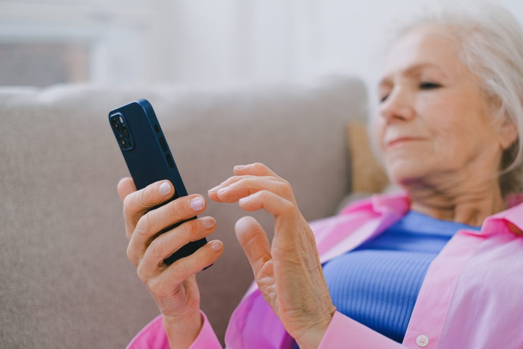 Older woman lying on couch with smartphone in her hand