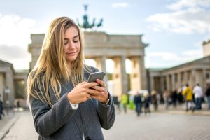 Blonde young girl using phone in front of Brandenburger Tor