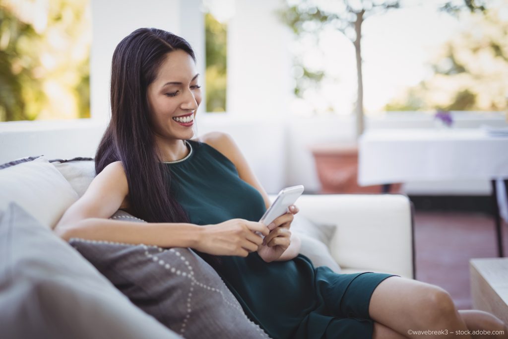 Businesswoman using mobile phone while sitting on sofa.